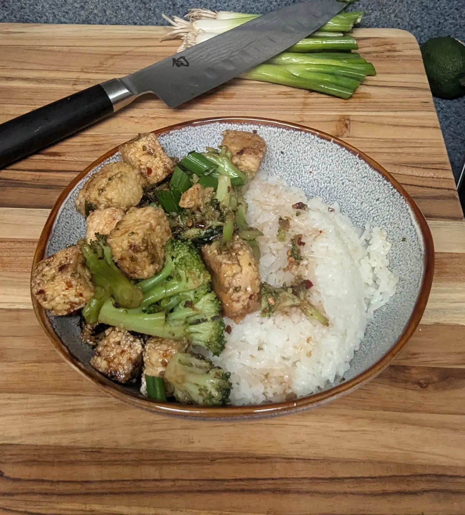 Tofu and broccoli stir-fry with rice on a wooden board